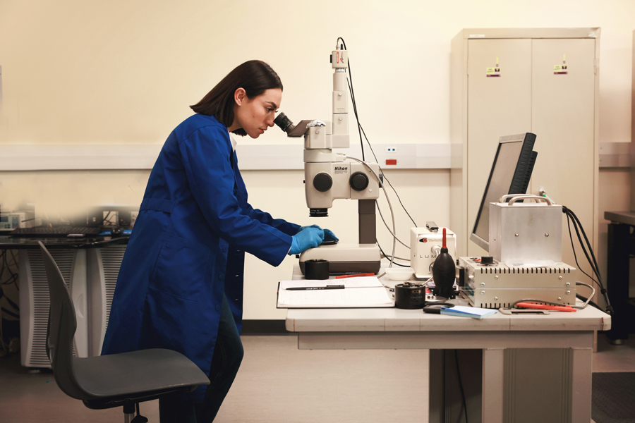 Ally Almaraz looking into a microscope in a lab.