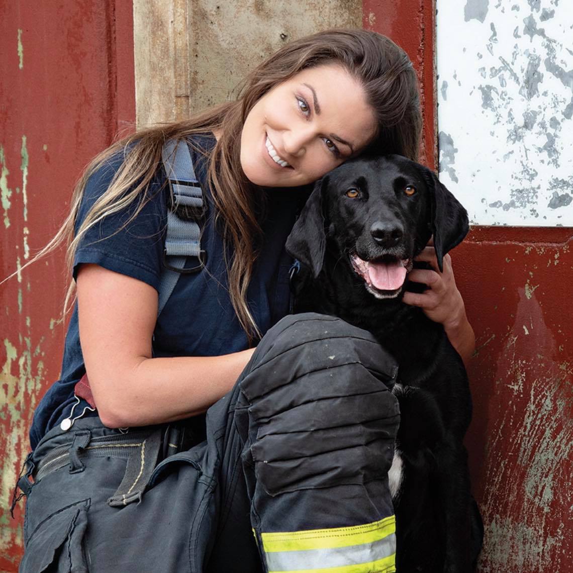 Sandra Rollings wearing a firefighter's uniform with a dog.